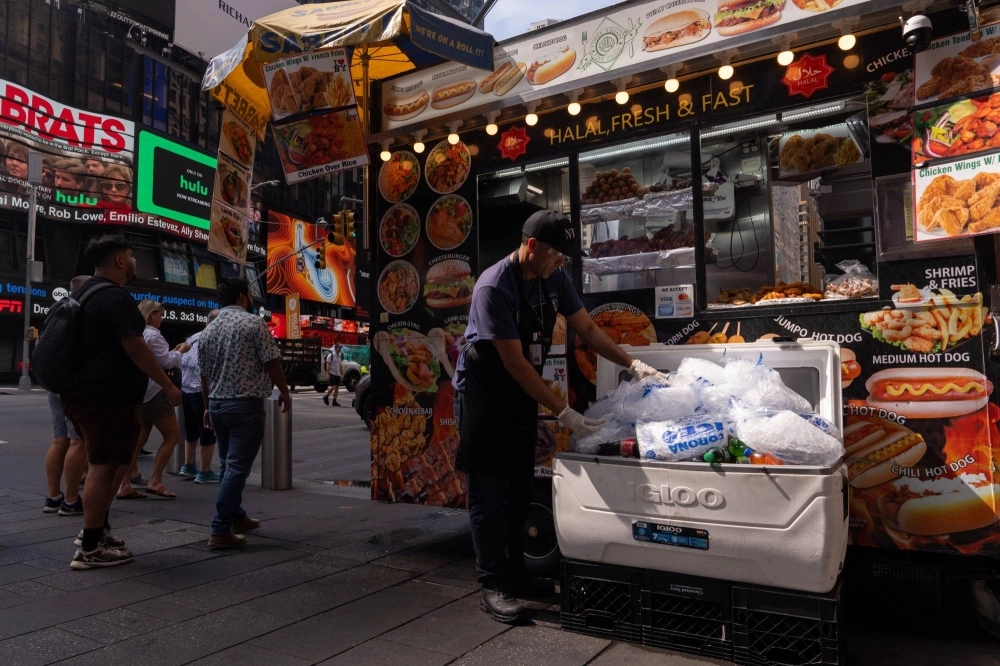 A food cart vendor places drinks under bags of ice in Times Square during high temperatures in New York.  A food cart vendor places drinks under bags of ice in Times Square during high temperatures in New York.