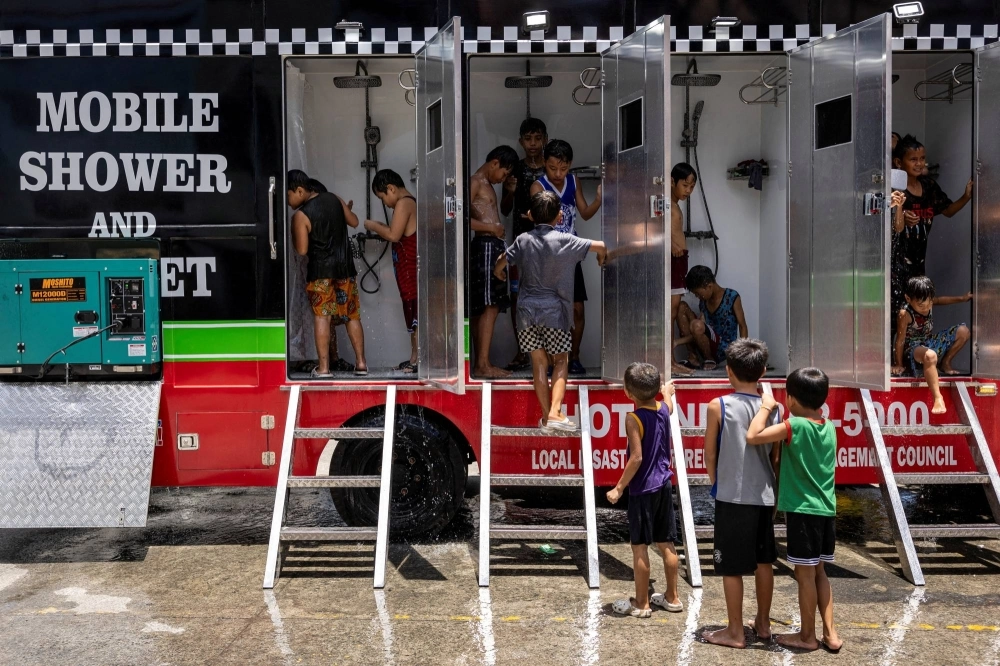 Children use a mobile shower, provided by the local government, amid extreme heat in metro Manila on May 2. Children use a mobile shower, provided by the local government, amid extreme heat in metro Manila on May 2.