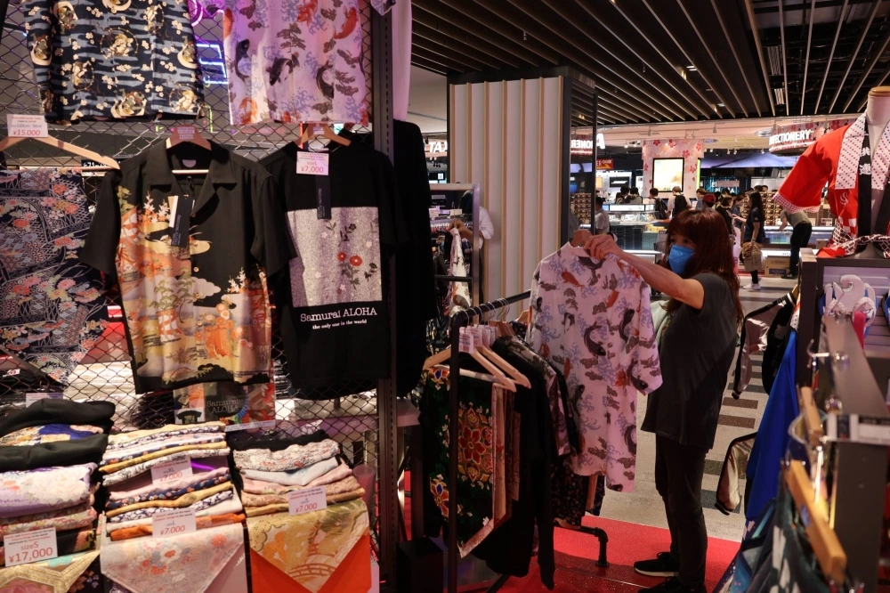 A tourist picks up an aloha shirt at the Samurai Aloha store at Narita Airport in June. A tourist picks up an aloha shirt at the Samurai Aloha store at Narita Airport in June.