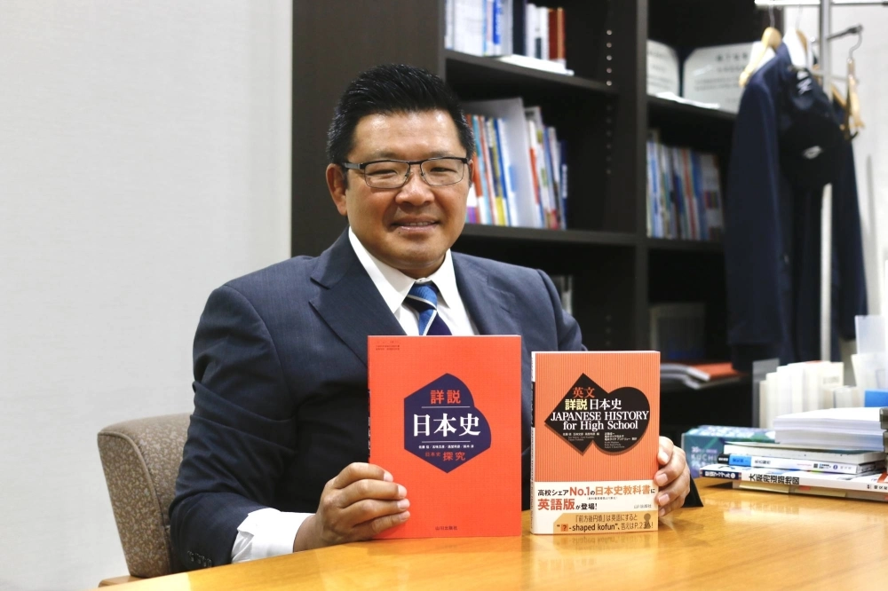 Yamakawa Shuppansha president Takeshi Nozawa holds the publisher's textbook on Japanese history — used in high schools across Japan — alongside the new English version in Tokyo on May 23. Yamakawa Shuppansha president Takeshi Nozawa holds the publisher's textbook on Japanese history — used in high schools across Japan — alongside the new English version in Tokyo on May 23.