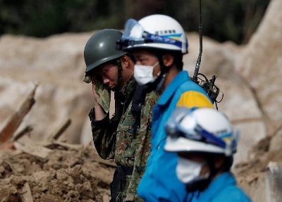 A member of the Self-Defense Forces wipes away sweat as he conducts a search and rescue operation at a landslide site caused by heavy rain in Kumano, Hiroshima Prefecture, on July 11, 2018. A member of the Self-Defense Forces wipes away sweat as he conducts a search and rescue operation at a landslide site caused by heavy rain in Kumano, Hiroshima Prefecture, on July 11, 2018.