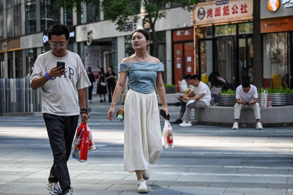Shoppers outside an office building in Beijing in August. China's overall public spending — which includes local governments — is shrinking, not growing. It contracted about 2% in the first seven months of 2024. Shoppers outside an office building in Beijing in August. China's overall public spending — which includes local governments — is shrinking, not growing. It contracted about 2% in the first seven months of 2024.
