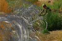 A member of the Texas National Guard places razor wire near the American border with Mexico, in El Paso, Texas, on Aug. 7.  | Reuters