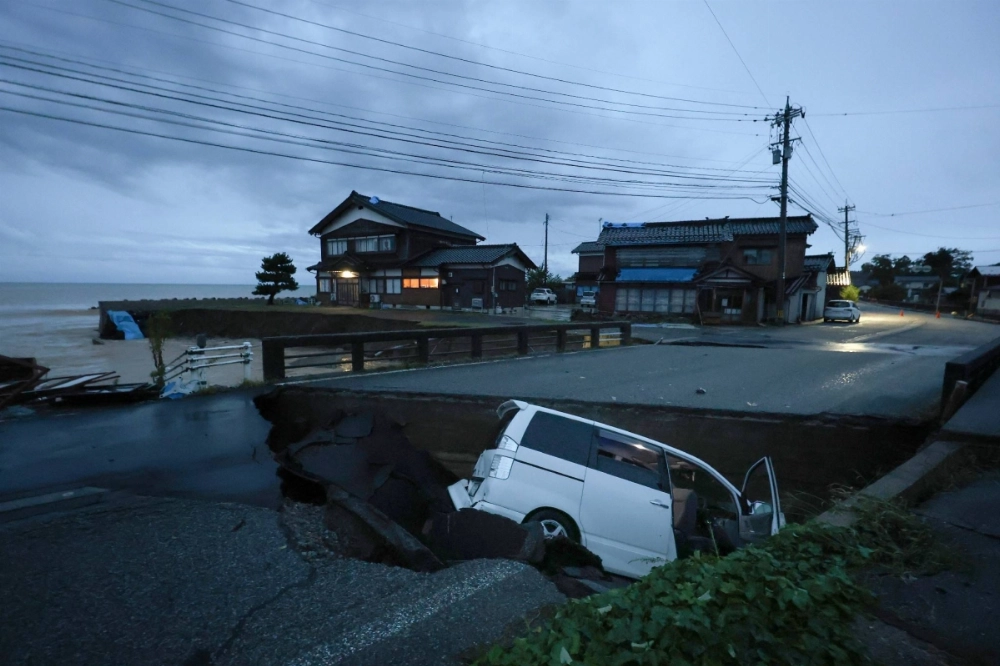 A car is seen in a crevice that opened up in a road amid heavy rains in Suzu, Ishikawa Prefecture, on Saturday. A car is seen in a crevice that opened up in a road amid heavy rains in Suzu, Ishikawa Prefecture, on Saturday.