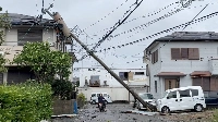 A person rides a scooter underneath a fallen pole following Typhoon Shanshan in Miyazaki on Aug. 29 in this screengrab taken from a social media video. | @bakuteman_8910 / via REUTERS