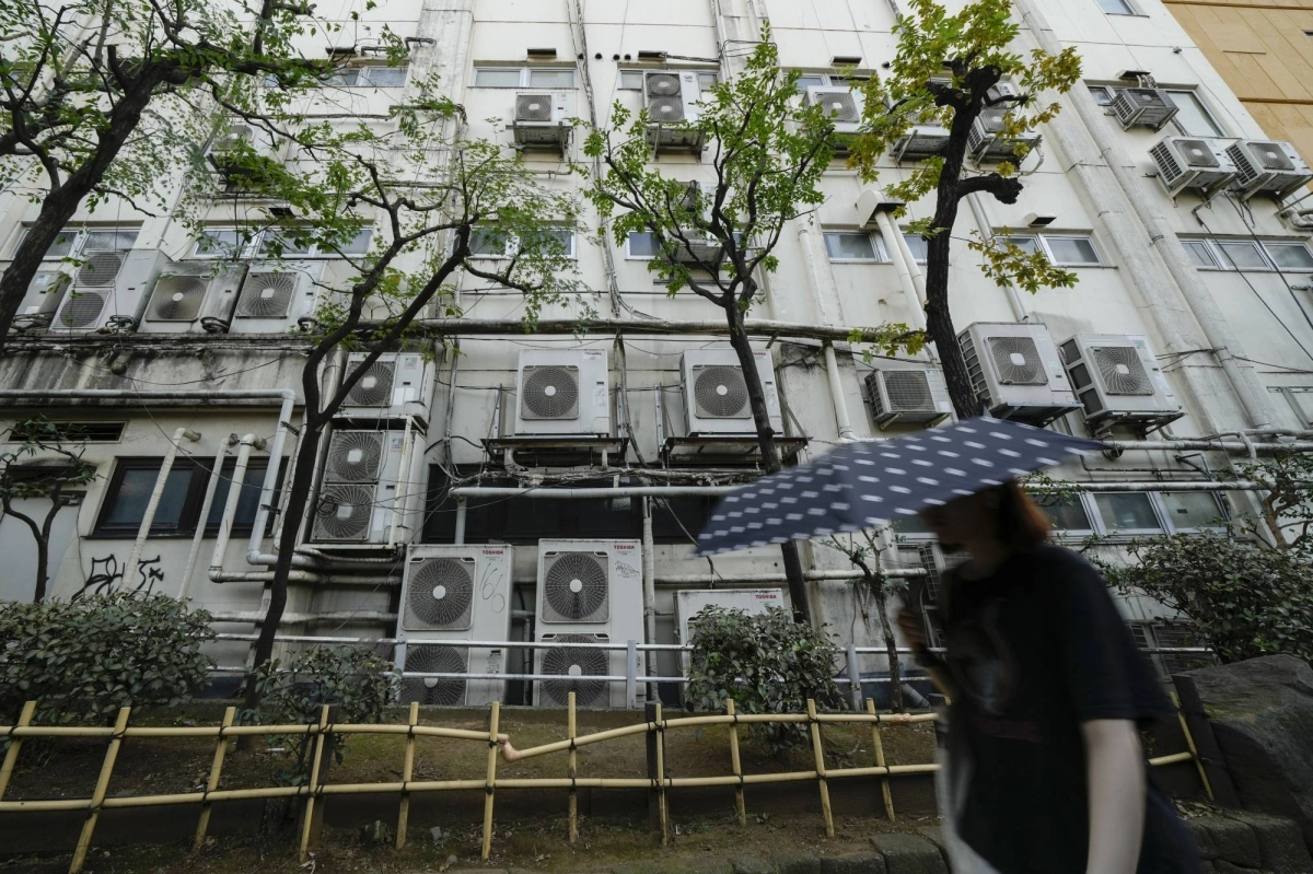 A pedestrian walks past air conditioning units in Tokyo on July 20. A pedestrian walks past air conditioning units in Tokyo on July 20.