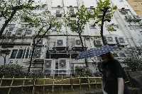 A pedestrian walks past air conditioning units in Tokyo on July 20. | Bloomberg