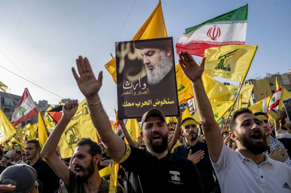 Supporters wave flags and salute during the broadcast of a speech by Hezbollah leader Hassan Nasrallah in Beirut in November 2023. Supporters wave flags and salute during the broadcast of a speech by Hezbollah leader Hassan Nasrallah in Beirut in November 2023.