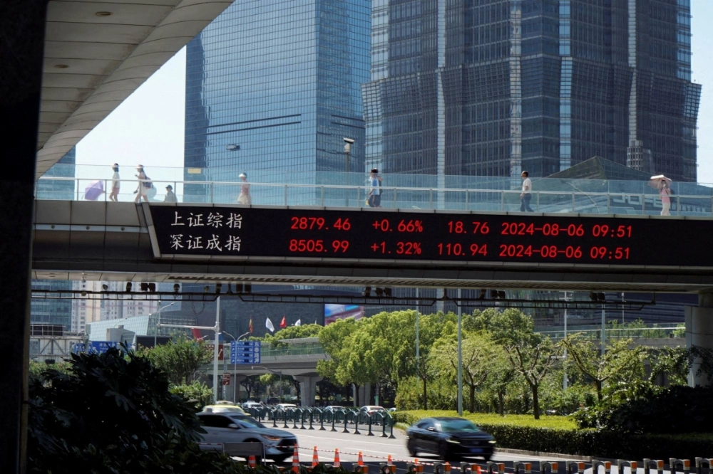 People walk on an overpass with a display of stock information in front of buildings in the Lujiazui financial district in Shanghai on Aug. 6. People walk on an overpass with a display of stock information in front of buildings in the Lujiazui financial district in Shanghai on Aug. 6.