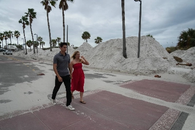 A couple from Orlando walks along a street covered in sand as a result of Hurricane Helene in Clearwater, Florida, ahead of Hurricane Milton's expected midweek landfall. A couple from Orlando walks along a street covered in sand as a result of Hurricane Helene in Clearwater, Florida, ahead of Hurricane Milton's expected midweek landfall.