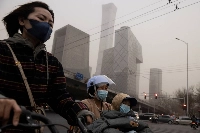 People wear face masks on a day with a high level of pollution in Beijing in March of last year.  | Reuters