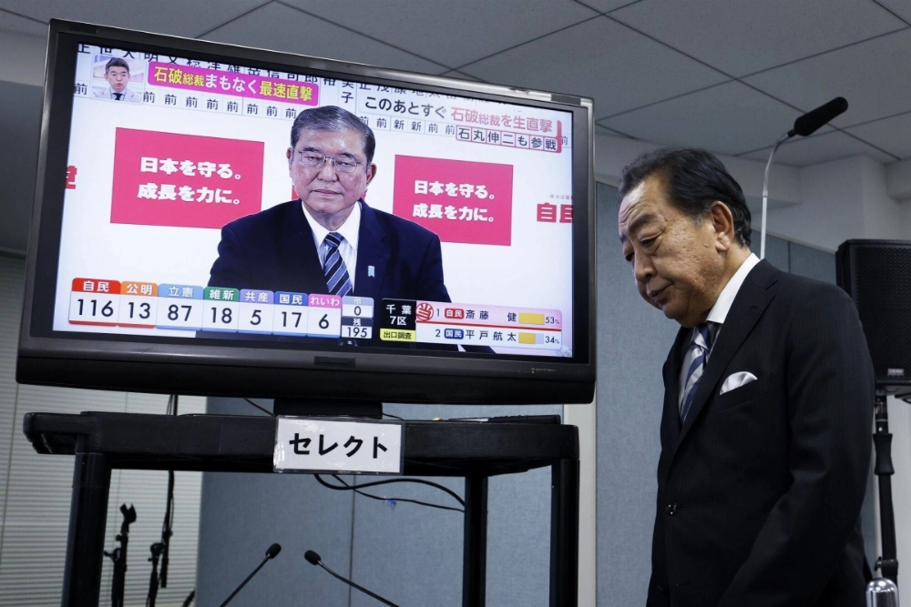 Yoshihiko Noda, head of the Constitutional Democratic Party of Japan, walks past a monitor displaying Prime Minister Shigeru Ishiba of the Liberal Democratic Party. Neither party gained a majority in Sunday's general election.  Yoshihiko Noda, head of the Constitutional Democratic Party of Japan, walks past a monitor displaying Prime Minister Shigeru Ishiba of the Liberal Democratic Party. Neither party gained a majority in Sunday's general election.