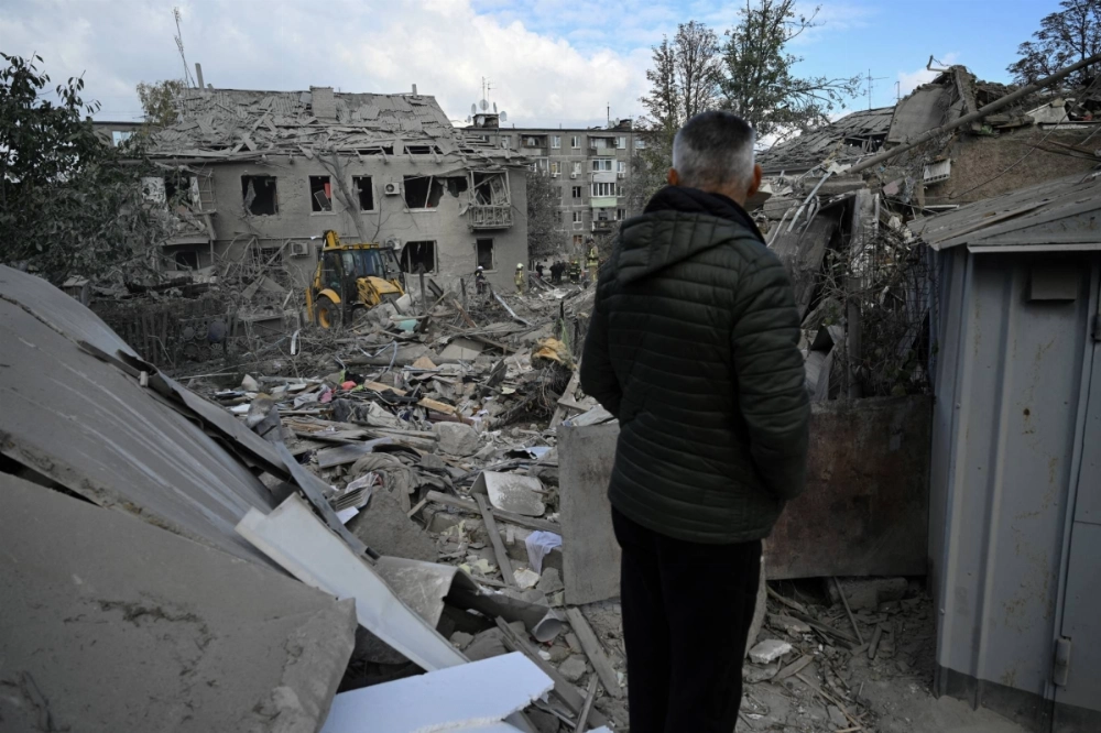 A local resident watches Ukrainian rescuers clear debris on the site of a Russian missile strike in Dnipro, Ukraine, on Saturday. A local resident watches Ukrainian rescuers clear debris on the site of a Russian missile strike in Dnipro, Ukraine, on Saturday.