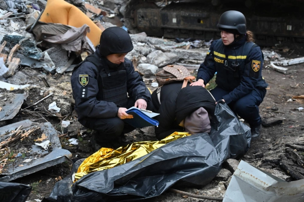 Ukrainian law enforcement officers comfort a woman crying over the body of her 15-year-old son following a missile attack in Kharkiv on Thursday.  Ukrainian law enforcement officers comfort a woman crying over the body of her 15-year-old son following a missile attack in Kharkiv on Thursday.