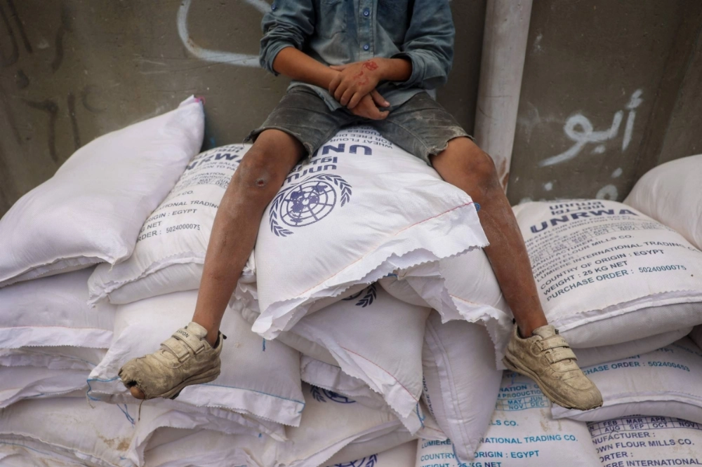 A Palestinian child sits on top of sacks of flour at a United Nations Relief and Works Agency (UNRWA) aid distribution center in Deir el-Balah in the central Gaza Strip on Sunday. A Palestinian child sits on top of sacks of flour at a United Nations Relief and Works Agency (UNRWA) aid distribution center in Deir el-Balah in the central Gaza Strip on Sunday.