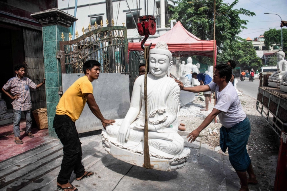 Workers unload a large marble Buddha statue from a truck in Mandalay, Myanmar. Workers unload a large marble Buddha statue from a truck in Mandalay, Myanmar.