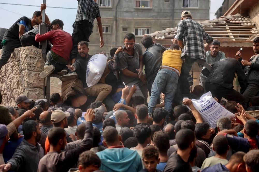 People scramble to receive sacks of flour at a United Nations Relief and Works Agency (UNRWA) aid distribution center in Deir el-Balah in the central Gaza Strip on Nov. 3. People scramble to receive sacks of flour at a United Nations Relief and Works Agency (UNRWA) aid distribution center in Deir el-Balah in the central Gaza Strip on Nov. 3.