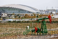 An oil pump jack and drilling rigs in an oilfield on the shore of the Caspian Sea, near the Aquatic Palace stadium in Baku, Azerbaijan, on Thursday. | Bloomberg