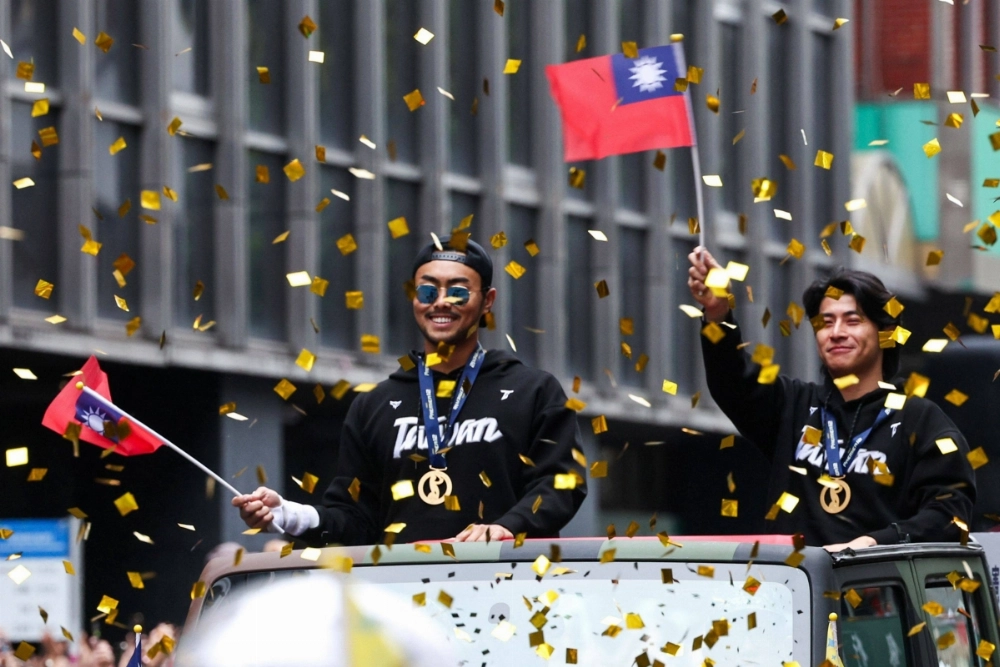 Chen Chieh-hsien, the captain of Taiwan's baseball team, waves to the crowd during a parade to celebrate the team winning the Premier12 title over Japan, on Tuesday in Taipei.  Chen Chieh-hsien, the captain of Taiwan's baseball team, waves to the crowd during a parade to celebrate the team winning the Premier12 title over Japan, on Tuesday in Taipei.