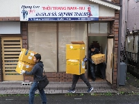 Investigators seize items after raiding a store in the city of Sakado, Saitama Prefecture, that is suspected to have been used by a Vietnamese theft ring as a collection point, on Wednesday. The store's signboard is partly blurred for privacy reasons. | Jiji