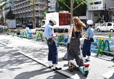 Police officers enforce electric scooter traffic regulations in Chuo Ward, Osaka, in July. Police officers enforce electric scooter traffic regulations in Chuo Ward, Osaka, in July.