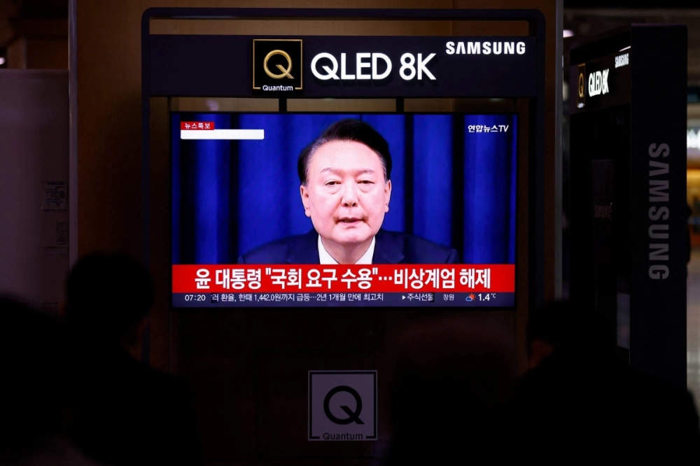 People watch South Korean President Yoon Suk Yeol's declaration of martial law and the following announcement that he will lift the martial law, after parliamentary vote, at a railway station in Seoul on Wednesday. People watch South Korean President Yoon Suk Yeol's declaration of martial law and the following announcement that he will lift the martial law, after parliamentary vote, at a railway station in Seoul on Wednesday.