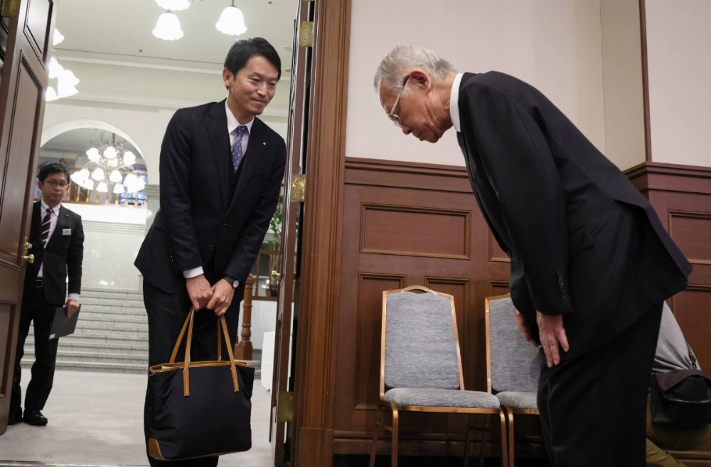 Yoshiki Taniguchi (right), mayor of Aioi, Hyogo Prefecture, apologizes to Hyogo Gov. Motohiko Saito ahead of a meeting between prefectural government officials and leaders of municipalities in the prefecture held in Kobe on Nov. 26. Taniguchi publicly questioned whether Saito had the credentials to become governor before his election. Yoshiki Taniguchi (right), mayor of Aioi, Hyogo Prefecture, apologizes to Hyogo Gov. Motohiko Saito ahead of a meeting between prefectural government officials and leaders of municipalities in the prefecture held in Kobe on Nov. 26. Taniguchi publicly questioned whether Saito had the credentials to become governor before his election.