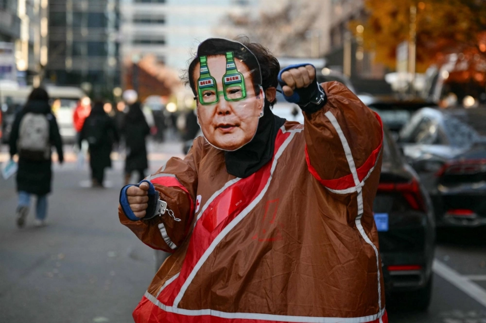 A man wearing a mask depicting South Korea President Yoon Suk Yeol dances on a street as people gather for a protest calling for the ouster of Yoon outside the National Assembly in Seoul on Saturday. A man wearing a mask depicting South Korea President Yoon Suk Yeol dances on a street as people gather for a protest calling for the ouster of Yoon outside the National Assembly in Seoul on Saturday.