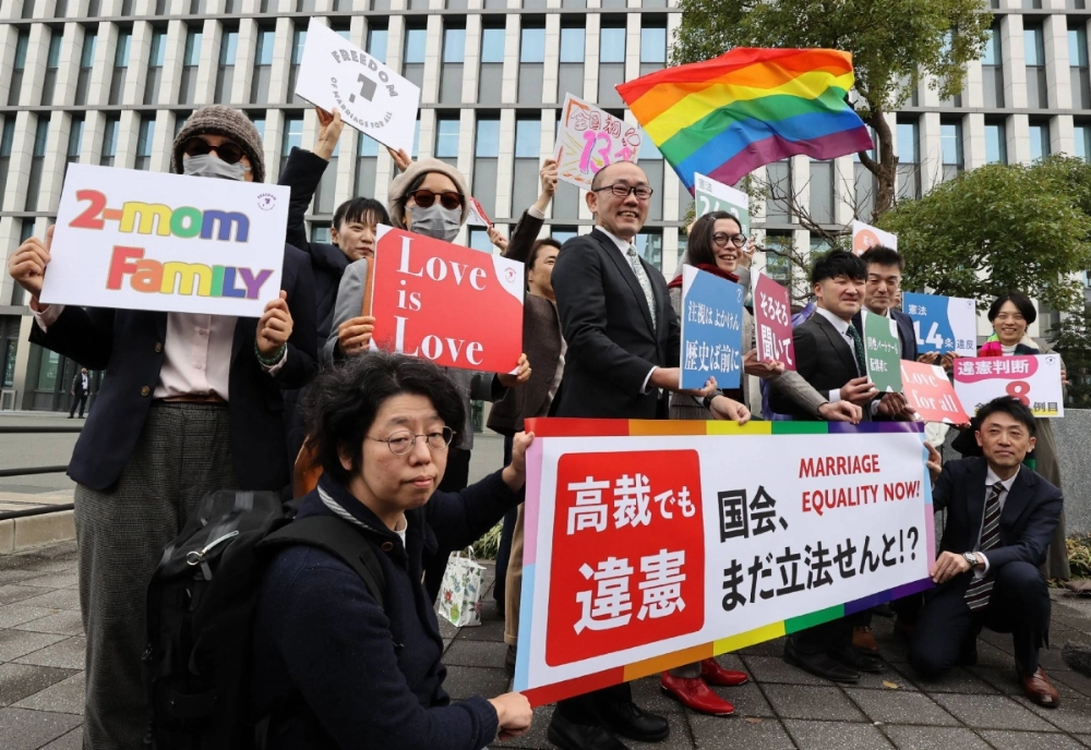 Plaintiffs in a lawsuit against Japan's same-sex marriage ban, along with their lawyers and supporters, hold signs saying the court ruled the ban as unconstitutional on Friday in front of the Fukuoka High Court. Plaintiffs in a lawsuit against Japan's same-sex marriage ban, along with their lawyers and supporters, hold signs saying the court ruled the ban as unconstitutional on Friday in front of the Fukuoka High Court.