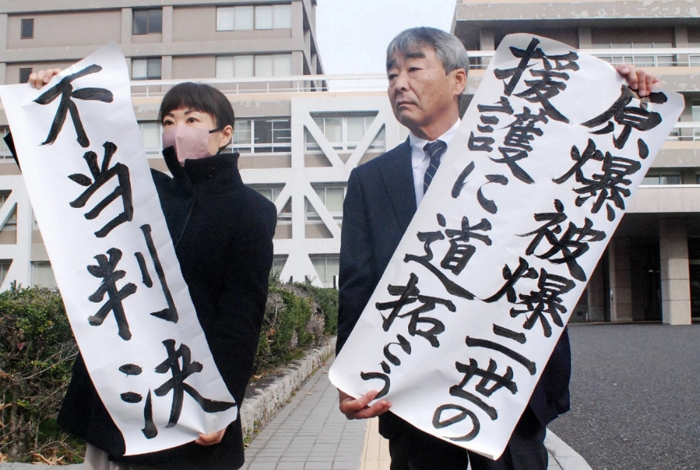 The plaintiffs' lawyers hold paper with phrases such as "unjust verdict," after the appeal court ruling in the second-generation hibakusha lawsuit, in Hiroshima Prefecture on Friday. The plaintiffs' lawyers hold paper with phrases such as "unjust verdict," after the appeal court ruling in the second-generation hibakusha lawsuit, in Hiroshima Prefecture on Friday.