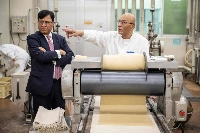 龜田制果株式會社董事長兼執行長 Lekh Juneja(左)於 8 月在新潟市公司總部的測試中心與一名員工交談。 | 法新社時事