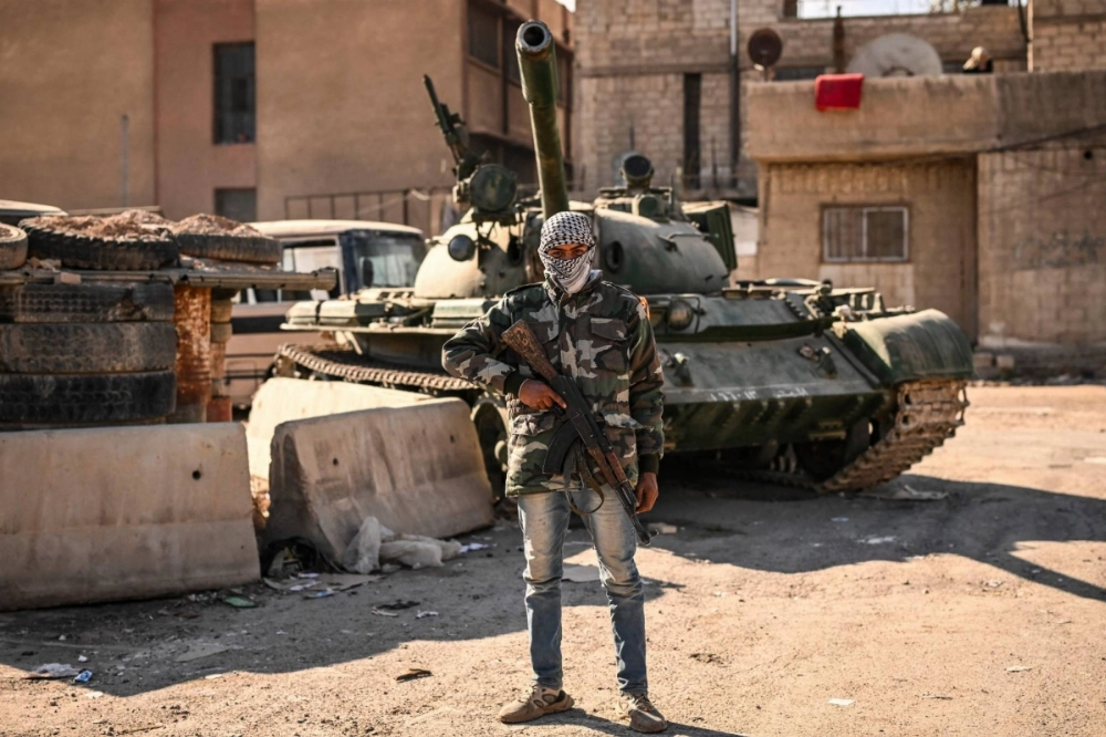 A rebel fighter stands in front of an abandoned tank in the town of Adra on the northeast outskirts of Damascus on Monday. A rebel fighter stands in front of an abandoned tank in the town of Adra on the northeast outskirts of Damascus on Monday.