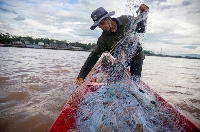 Boonrat Chaikeaw hauls in a net full of trash as he fishes in the Mekong River by Chiang Khong on the border of Thailand and Laos. | Anton L. Delgado