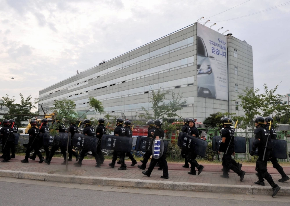 Riot police march in front of the main building of Ssangyong Motor in Pyeongtaek, 70 kilometers south of Seoul, on Aug. 6, 2009.  Riot police march in front of the main building of Ssangyong Motor in Pyeongtaek, 70 kilometers south of Seoul, on Aug. 6, 2009.
