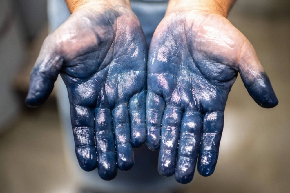 The hands of dyeing craftsman Yoshiharu Okamoto are stained a deep blue by his work with indigo. The hands of dyeing craftsman Yoshiharu Okamoto are stained a deep blue by his work with indigo.