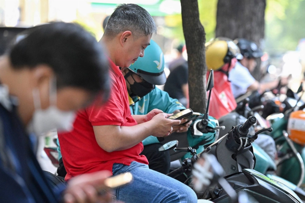 People use their smartphones as they sit on motorbikes in Ho Chi Minh City on Monday.  People use their smartphones as they sit on motorbikes in Ho Chi Minh City on Monday.