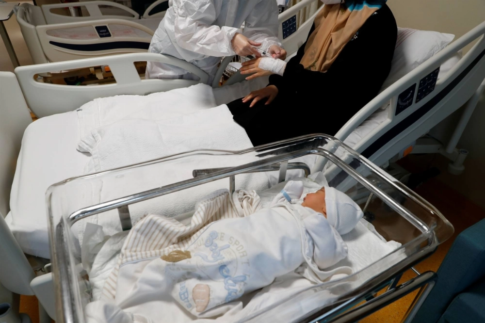 A member of the medical staff treats a woman with COVID-19 next to her four-day-old baby at a hospital in Istanbul, Turkey, in November 2021. A member of the medical staff treats a woman with COVID-19 next to her four-day-old baby at a hospital in Istanbul, Turkey, in November 2021.