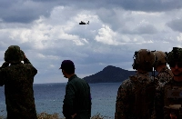 A Ground Self-Defense Force helicopter flies over GSDF's Amphibious Rapid Deployment Brigade soldiers and U.S. Marines during a drill in Okinawa last year.  | Reuters