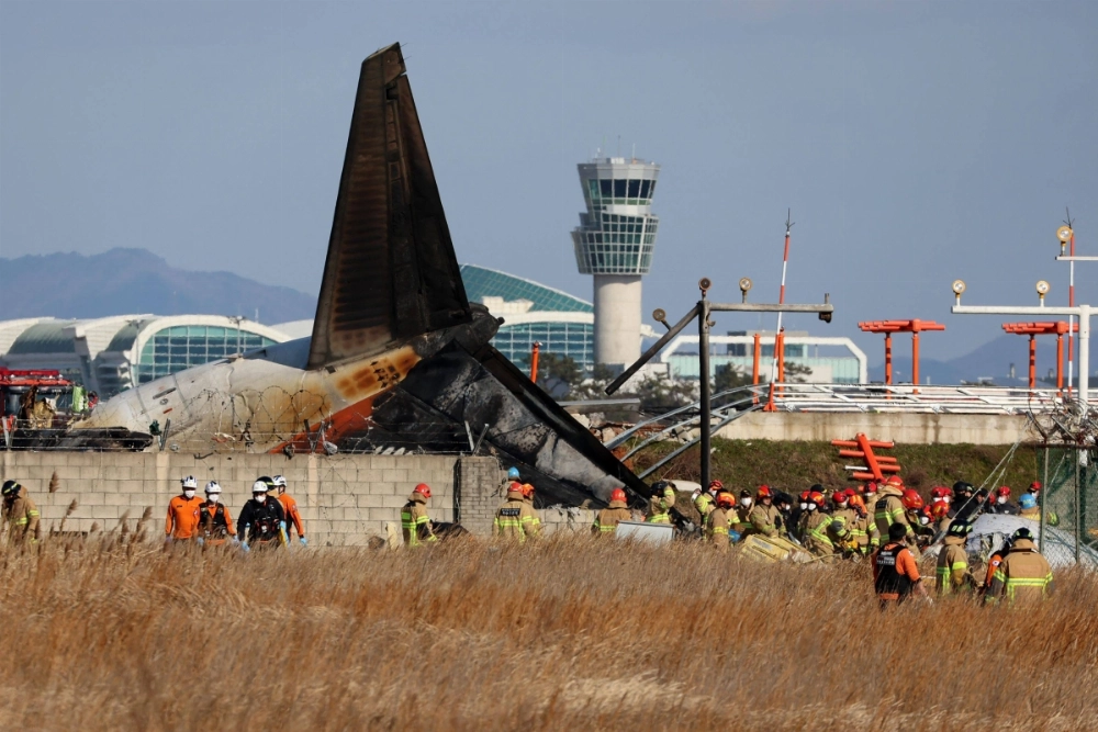 Rescue personnel are seen near the tail section of a Jeju Air Boeing 737-800 series aircraft after the plane crashed and burst into flames at Muan International Airport in Muan, South Korea, on Sunday. Rescue personnel are seen near the tail section of a Jeju Air Boeing 737-800 series aircraft after the plane crashed and burst into flames at Muan International Airport in Muan, South Korea, on Sunday.