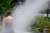 A pedestrian walks under cooling mist sprays in the Ginza district of Tokyo in July. This year, the Environment Ministry issued 1,722 heatstroke alerts across Japan, a record high since the ministry started issuing them in 2020.  | Bloomberg