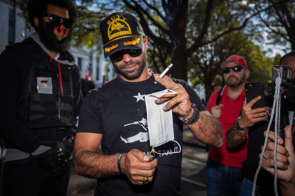 Enrique Tarrio, leader of the Proud Boys, lights a protective face mask on fire during a rally in support of President Donald Trump in Atlanta, in 2020.  Enrique Tarrio, leader of the Proud Boys, lights a protective face mask on fire during a rally in support of President Donald Trump in Atlanta, in 2020.