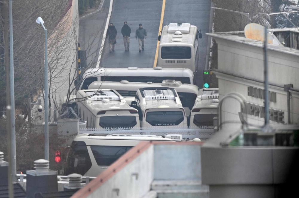 Security personnel walk on the road with buses blocking an entrance gate to protect impeached South Korean President Yoon Suk Yeol from a possible second arrest attempt by the Corruption Investigation Office for High-ranking Officials in Seoul on Monday. Security personnel walk on the road with buses blocking an entrance gate to protect impeached South Korean President Yoon Suk Yeol from a possible second arrest attempt by the Corruption Investigation Office for High-ranking Officials in Seoul on Monday.