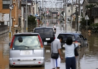 Local residents wade through a residential area flooded by the Kinugawa river, caused by Typhoon Etau, in Joso, Ibaraki Prefecture, in September 2015. | REUTERS