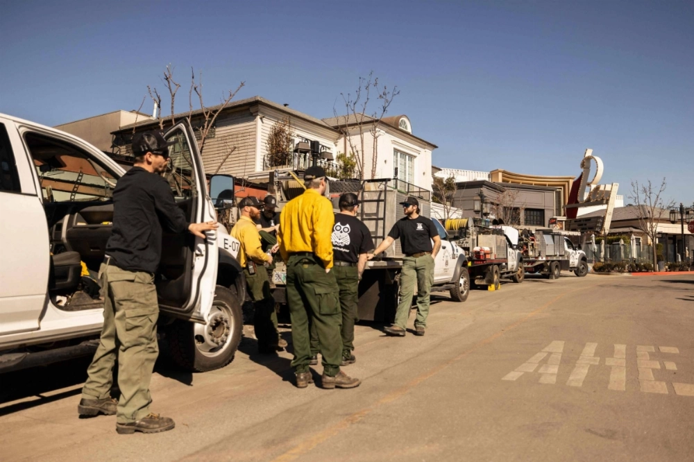 Private firefighters gather near their vehicles at a mall in Pacific Palisades, California, on Wednesday. Private firefighters gather near their vehicles at a mall in Pacific Palisades, California, on Wednesday.
