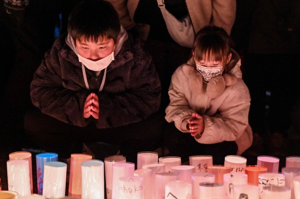 Children pray for the victims of the Great Hanshin-Awaji Earthquake during an early morning ceremony to mark the 30th anniversary of the quake, in Kobe on Friday. Children pray for the victims of the Great Hanshin-Awaji Earthquake during an early morning ceremony to mark the 30th anniversary of the quake, in Kobe on Friday.