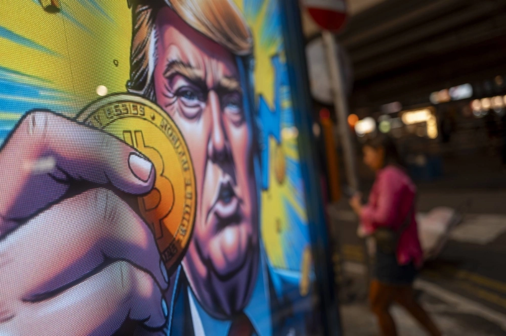 A cartoon image of U.S. President-elect Donald Trump holding a Bitcoin token to mark the cryptocurrency reaching over $100,000 is displayed at a Coinhero store in Hong Kong on Dec. 5. A cartoon image of U.S. President-elect Donald Trump holding a Bitcoin token to mark the cryptocurrency reaching over $100,000 is displayed at a Coinhero store in Hong Kong on Dec. 5.