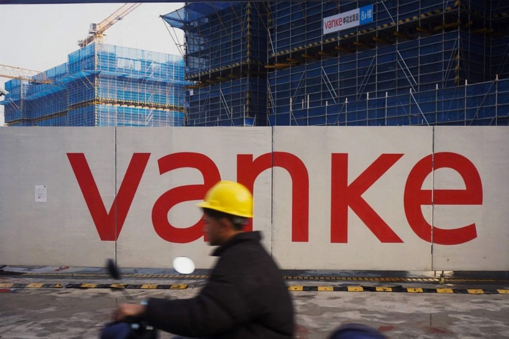 A worker drives past residential buildings under construction by Chinese real estate developer Vanke in Hangzhou, in eastern China's Zhejiang province. The indebted Chinese property developer warned on Monday that it incurred major losses in 2024, a filing at the Hong Kong Stock Exchange showed. A worker drives past residential buildings under construction by Chinese real estate developer Vanke in Hangzhou, in eastern China's Zhejiang province. The indebted Chinese property developer warned on Monday that it incurred major losses in 2024, a filing at the Hong Kong Stock Exchange showed.