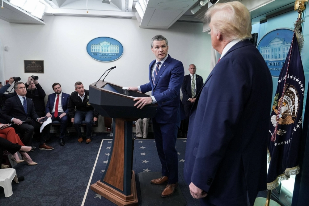 U.S. President Donald Trump looks on as his defense chief, Pete Hegseth, speaks about the midair crash between a passenger jet and U.S. Army helicopter on Thursday.  U.S. President Donald Trump looks on as his defense chief, Pete Hegseth, speaks about the midair crash between a passenger jet and U.S. Army helicopter on Thursday.