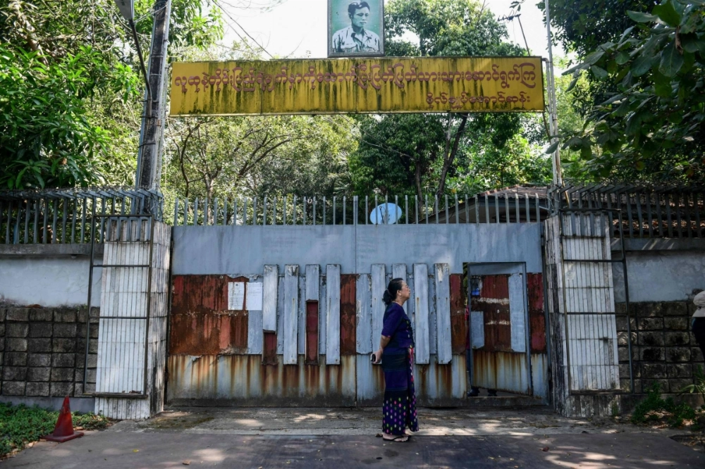 A woman stands outside the gates of the family house of detained Myanmar civilian leader Aung San Suu Kyi in Yangon, Myanmar, on Wednesday, during an attempt to sell the lakeside mansion. A woman stands outside the gates of the family house of detained Myanmar civilian leader Aung San Suu Kyi in Yangon, Myanmar, on Wednesday, during an attempt to sell the lakeside mansion.