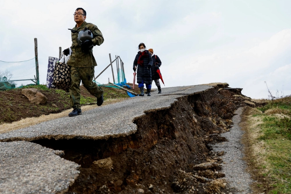 A Self-Defense Forces member leads residents in Fukamimachi, a village in Wajima, Ishikawa Prefecture, to a rescue helicopter, on a destroyed road in January last year. A Self-Defense Forces member leads residents in Fukamimachi, a village in Wajima, Ishikawa Prefecture, to a rescue helicopter, on a destroyed road in January last year.